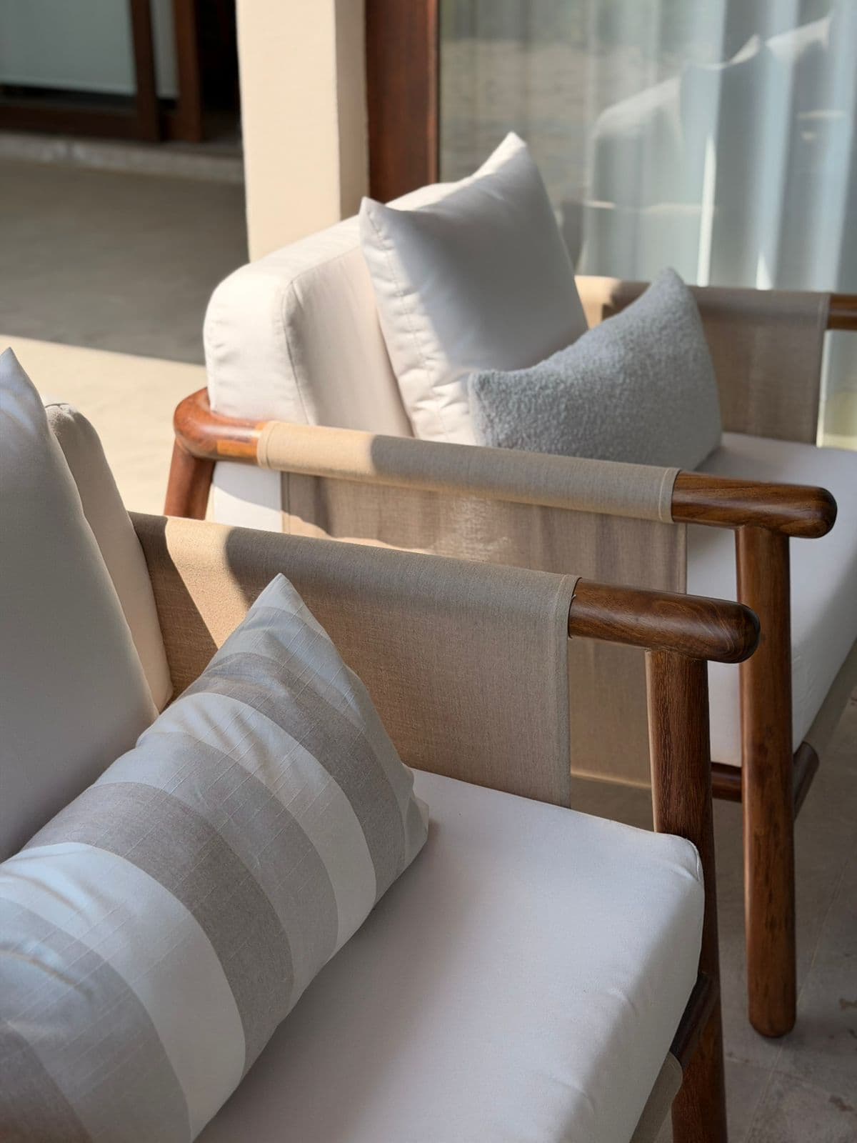 Mobiliario de exterior con sillones de madera y cojines claros